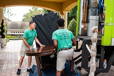 two people lifting a table onto a trucks lift gate