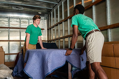 two people moving a covered table in a truck